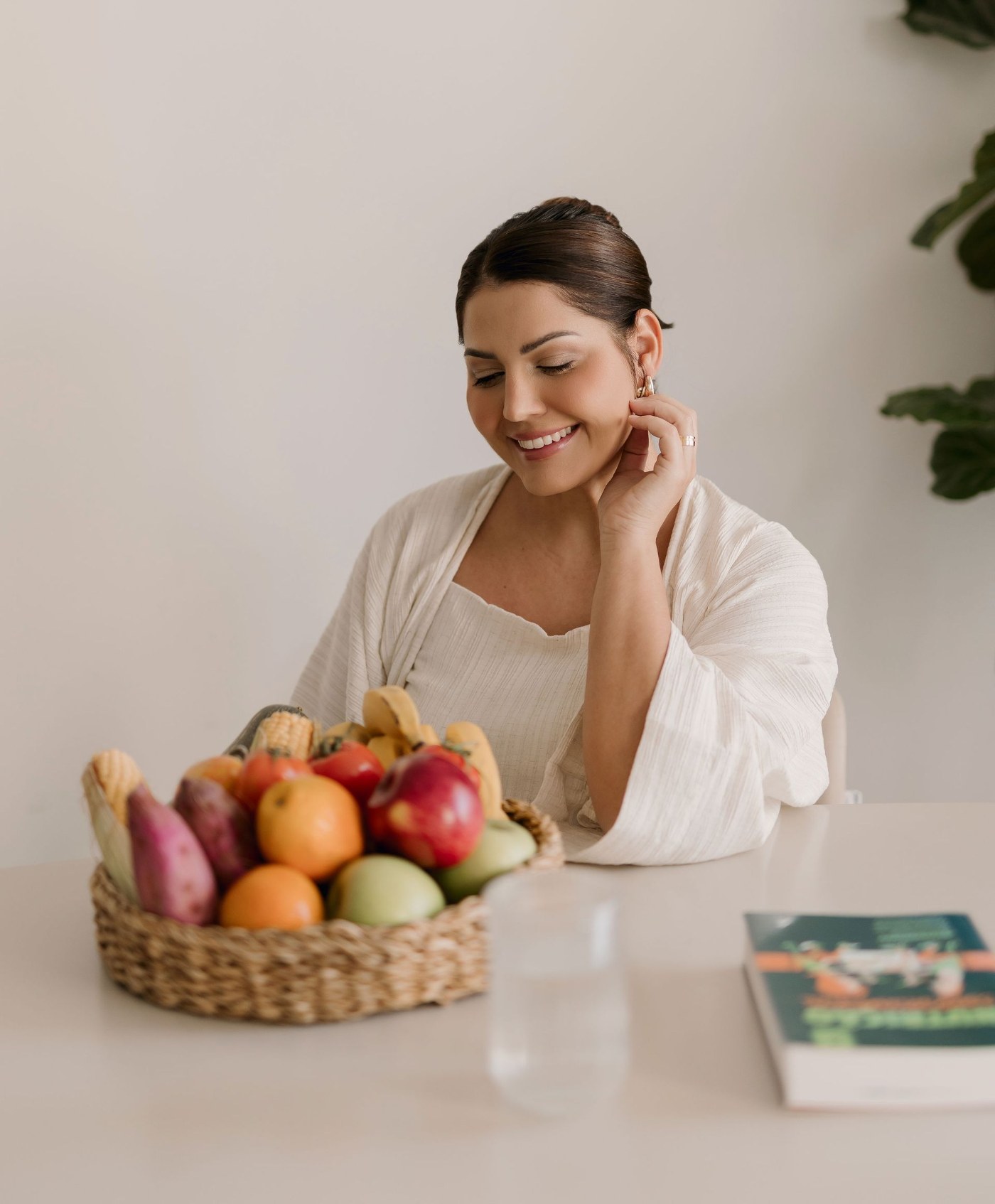 Daniela Muller sorrindo à mesa com uma cesta de frutas